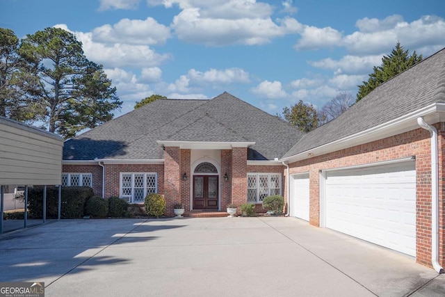 view of front of property with a garage, a shingled roof, concrete driveway, french doors, and brick siding