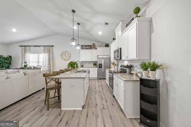 kitchen featuring pendant lighting, a center island with sink, a breakfast bar area, stainless steel appliances, and open floor plan