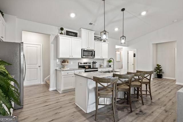 kitchen featuring visible vents, a sink, appliances with stainless steel finishes, light wood-style floors, and lofted ceiling