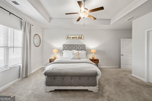 bedroom featuring baseboards, a raised ceiling, visible vents, and light colored carpet