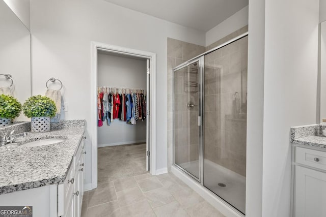 bathroom with a stall shower, a spacious closet, baseboards, and vanity