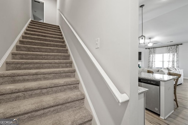 stairway with ceiling fan, baseboards, and wood finished floors