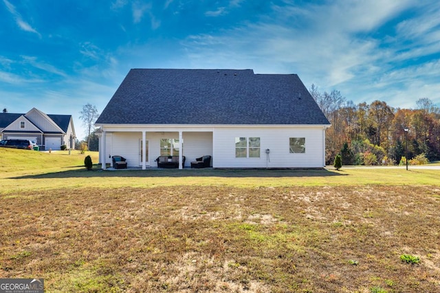 back of house with roof with shingles and a lawn