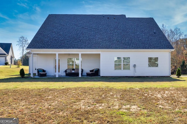 back of house featuring a shingled roof and a lawn