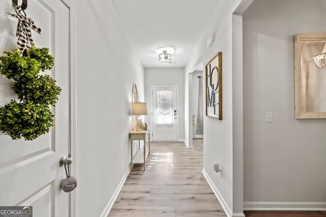 hall featuring light wood-type flooring and baseboards