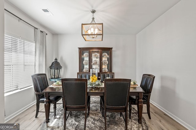 dining room with wood finished floors, an inviting chandelier, baseboards, and visible vents