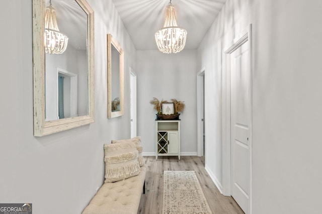 hallway with a chandelier, light wood-style flooring, and baseboards