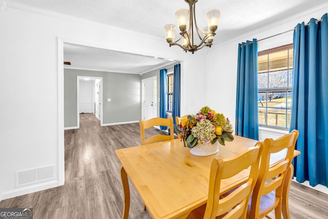 dining area featuring a textured ceiling, crown molding, and wood finished floors