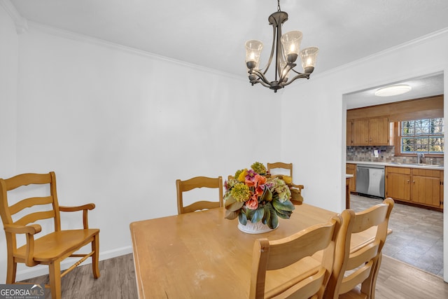 dining room featuring a chandelier, light wood-style floors, baseboards, and crown molding