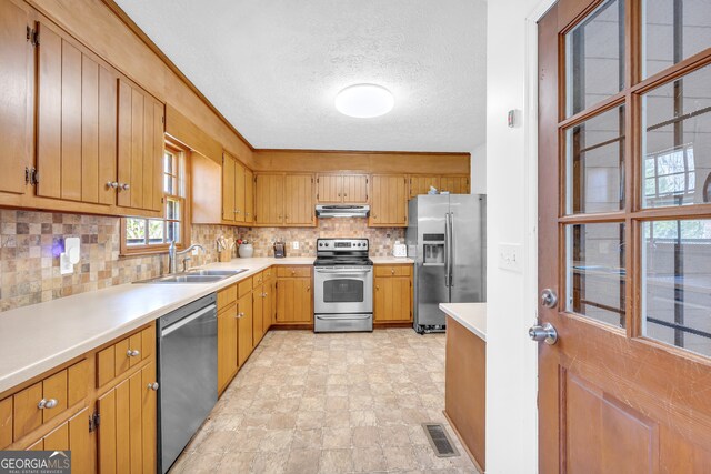 kitchen featuring light countertops, visible vents, appliances with stainless steel finishes, a sink, and under cabinet range hood