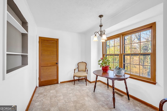 sitting room featuring a textured ceiling, a notable chandelier, visible vents, and baseboards