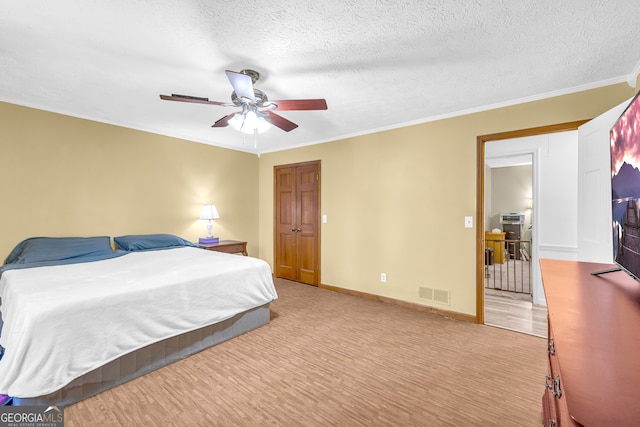 bedroom with a textured ceiling, visible vents, baseboards, light wood-type flooring, and crown molding