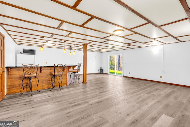 interior space featuring hanging light fixtures, a bar, wood finished floors, and baseboards