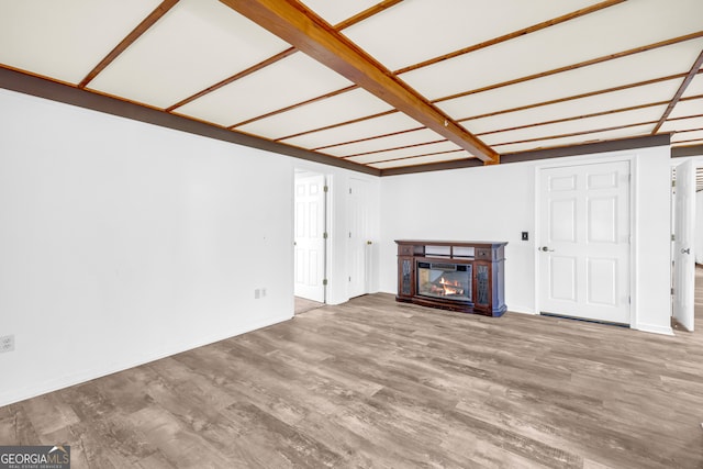 unfurnished living room with baseboards, wood finished floors, and a glass covered fireplace