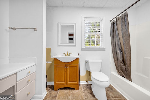 bathroom featuring shower / tub combo, baseboards, toilet, vanity, and a paneled ceiling