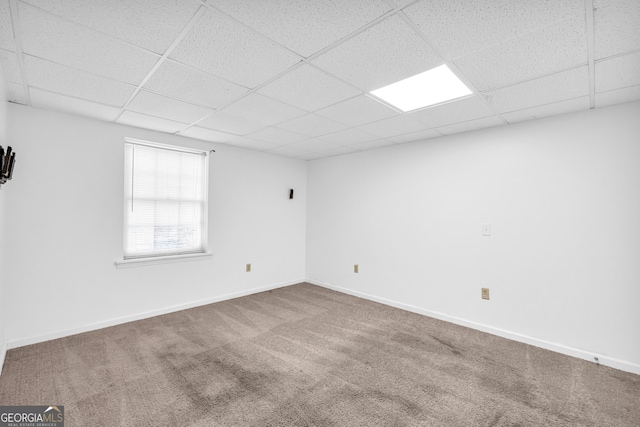 carpeted empty room with a drop ceiling and baseboards