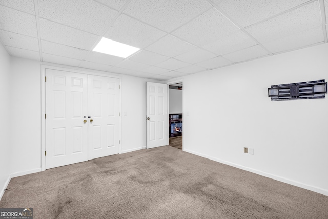 finished below grade area featuring carpet floors, a drop ceiling, and baseboards