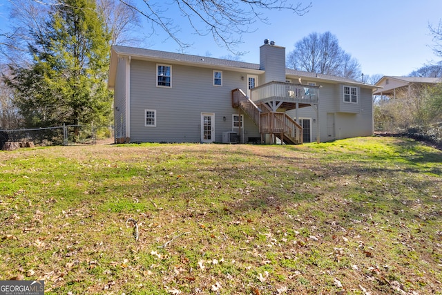 rear view of house featuring fence, stairway, a lawn, a wooden deck, and a chimney