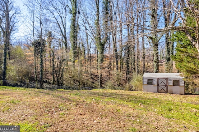 view of yard featuring an outbuilding and a view of trees