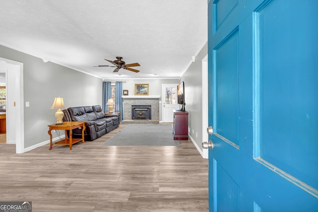 living area with a textured ceiling, crown molding, and wood finished floors