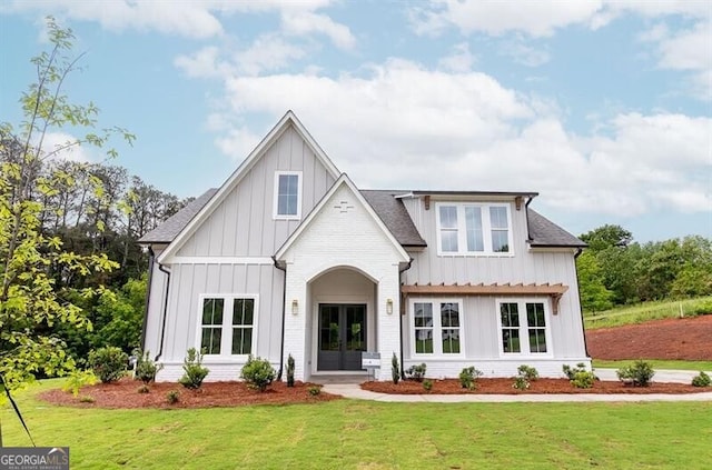 view of front of property with a front lawn, board and batten siding, and french doors