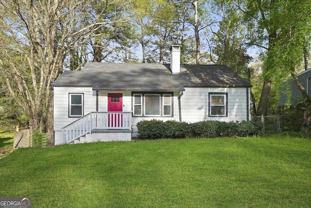 view of front of home with a chimney, fence, and a front lawn