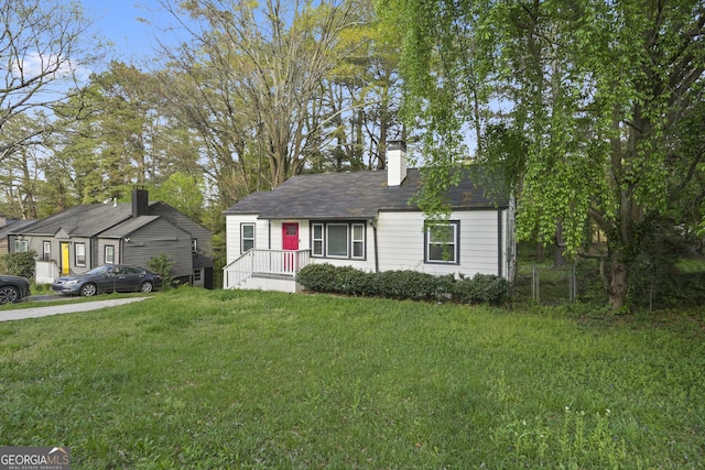 view of front of house featuring a chimney, fence, and a front lawn