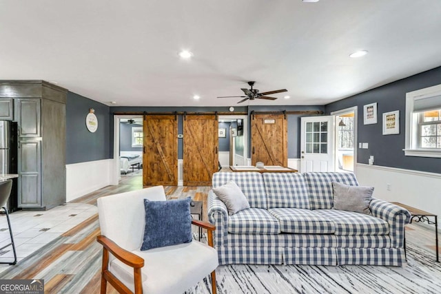 living room featuring recessed lighting, a wainscoted wall, ceiling fan, and a barn door