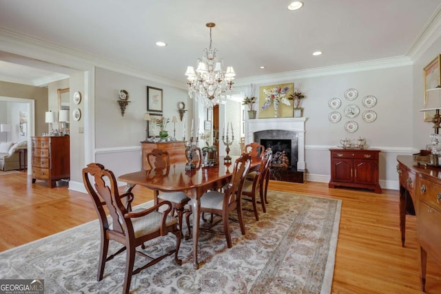 dining area featuring light wood finished floors, a fireplace, baseboards, and crown molding