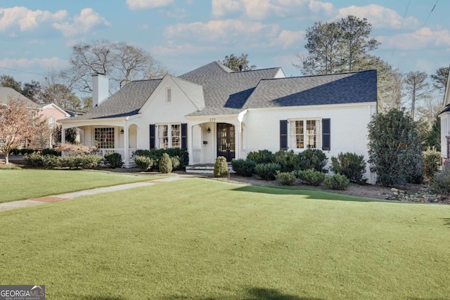 view of front of house with a chimney, a front lawn, and roof with shingles