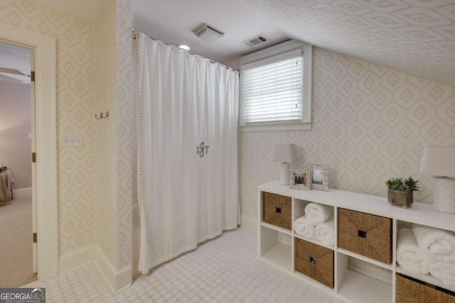 interior space featuring lofted ceiling, baseboards, visible vents, and wallpapered walls