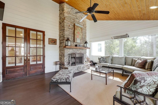 sunroom with a ceiling fan, french doors, wood ceiling, vaulted ceiling, and a stone fireplace