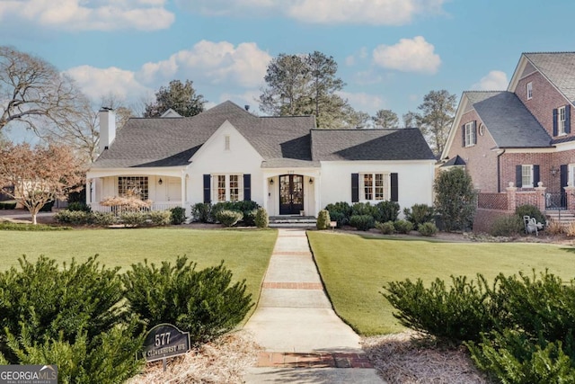 french country home with a chimney and a front lawn