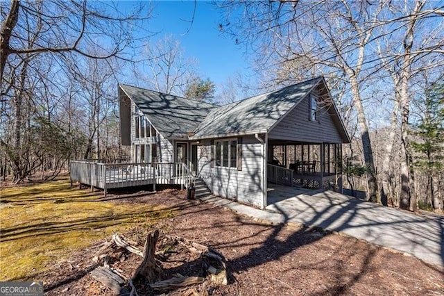 view of home's exterior featuring a shingled roof, concrete driveway, a carport, and a wooden deck