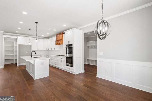 kitchen featuring appliances with stainless steel finishes, dark wood-type flooring, light countertops, crown molding, and a sink