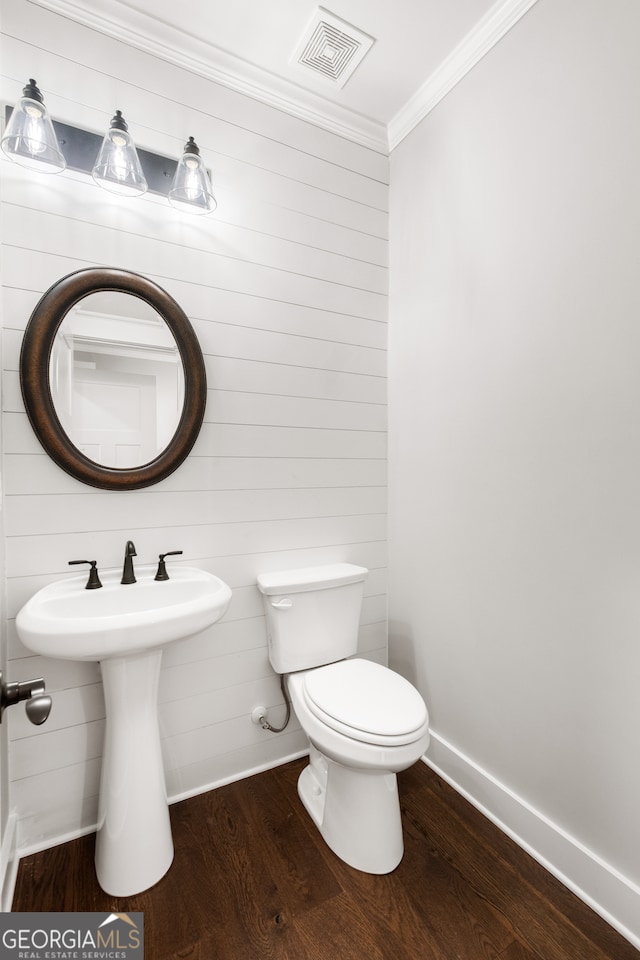 half bathroom featuring crown molding, visible vents, toilet, wood finished floors, and baseboards