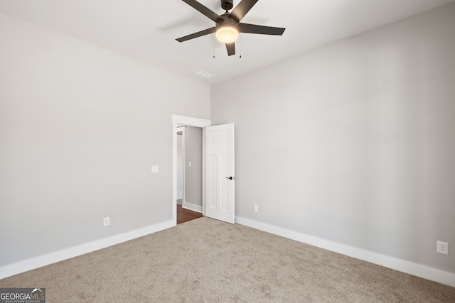 spare room with dark colored carpet, ceiling fan, and baseboards