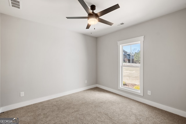 carpeted empty room featuring a ceiling fan, visible vents, and baseboards