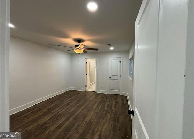 spare room with dark wood-type flooring, visible vents, baseboards, and a ceiling fan