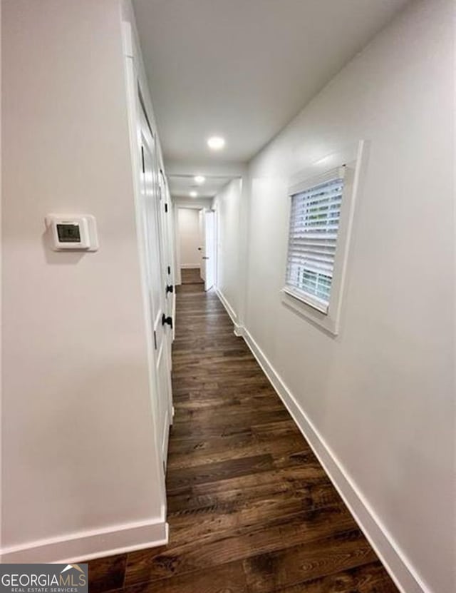 hallway with dark wood finished floors and baseboards