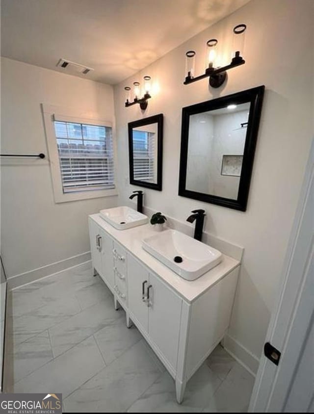 full bathroom featuring marble finish floor, a sink, and baseboards