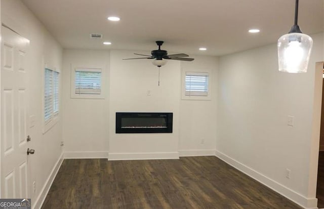 unfurnished living room featuring dark wood-style floors, a glass covered fireplace, visible vents, and recessed lighting