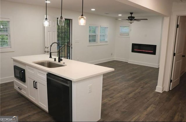 kitchen featuring light countertops, hanging light fixtures, white cabinets, a kitchen island with sink, and a sink