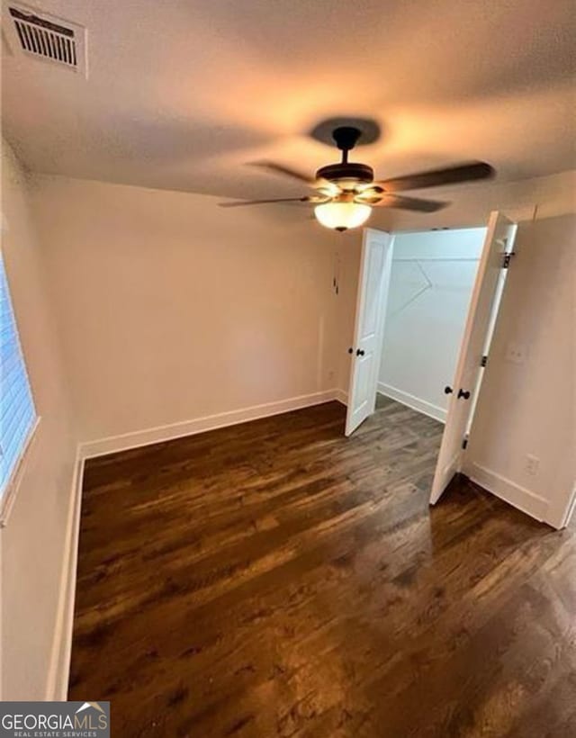 unfurnished bedroom featuring dark wood-type flooring, visible vents, a textured ceiling, and baseboards