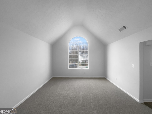 additional living space featuring lofted ceiling, baseboards, visible vents, and a textured ceiling