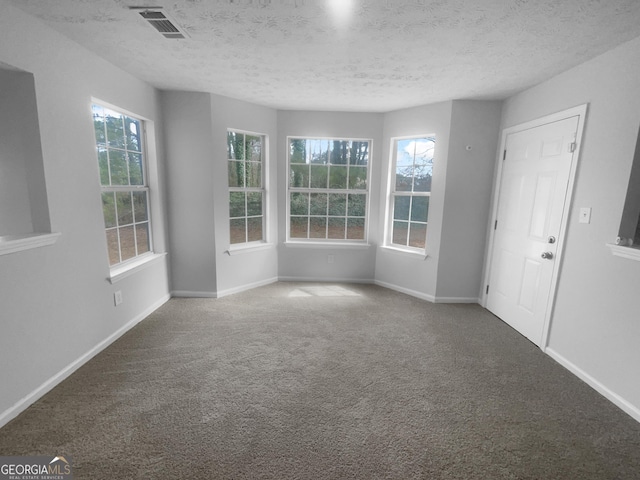 empty room with a textured ceiling, carpet, and baseboards