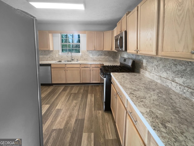 kitchen with light countertops, appliances with stainless steel finishes, a sink, and light brown cabinetry