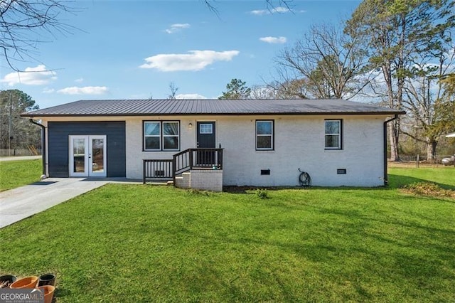 rear view of property with crawl space, metal roof, and a yard