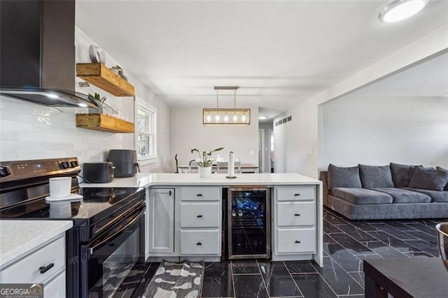 kitchen with wine cooler, a peninsula, black range with electric stovetop, light countertops, and decorative light fixtures