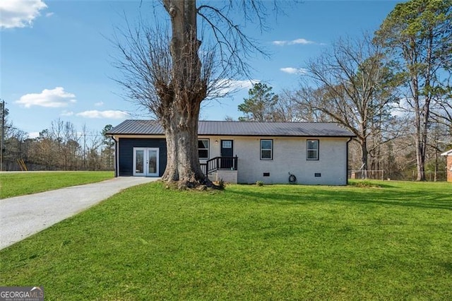 ranch-style house with metal roof, concrete driveway, french doors, crawl space, and a front lawn